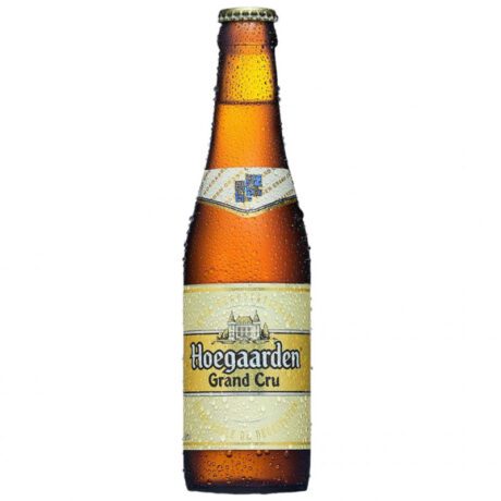 Botella de Hoegaarden Grand Cru junto a un vaso con cerveza dorada turbia y espuma blanca